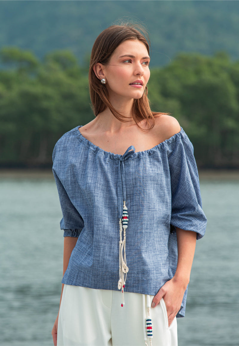 Modelo vestindo uma túnica marinho de mangas bufantes com cordão decorativo e short preto branco.