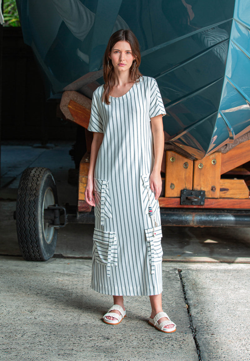 Modelo veste um vestido longo de mangas curtas com listras verticais em cinza e grandes bolsos utilitários frontais.