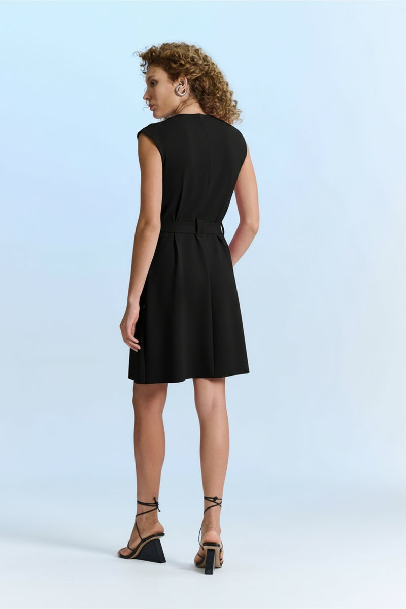 Modelo de costas exibe a parte traseira de um vestido curto preto de tecido fluido.