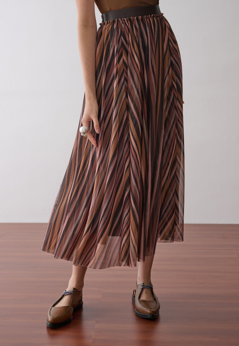 Modelo veste uma saia longa plissada em tule com estampa de listras multicoloridas.