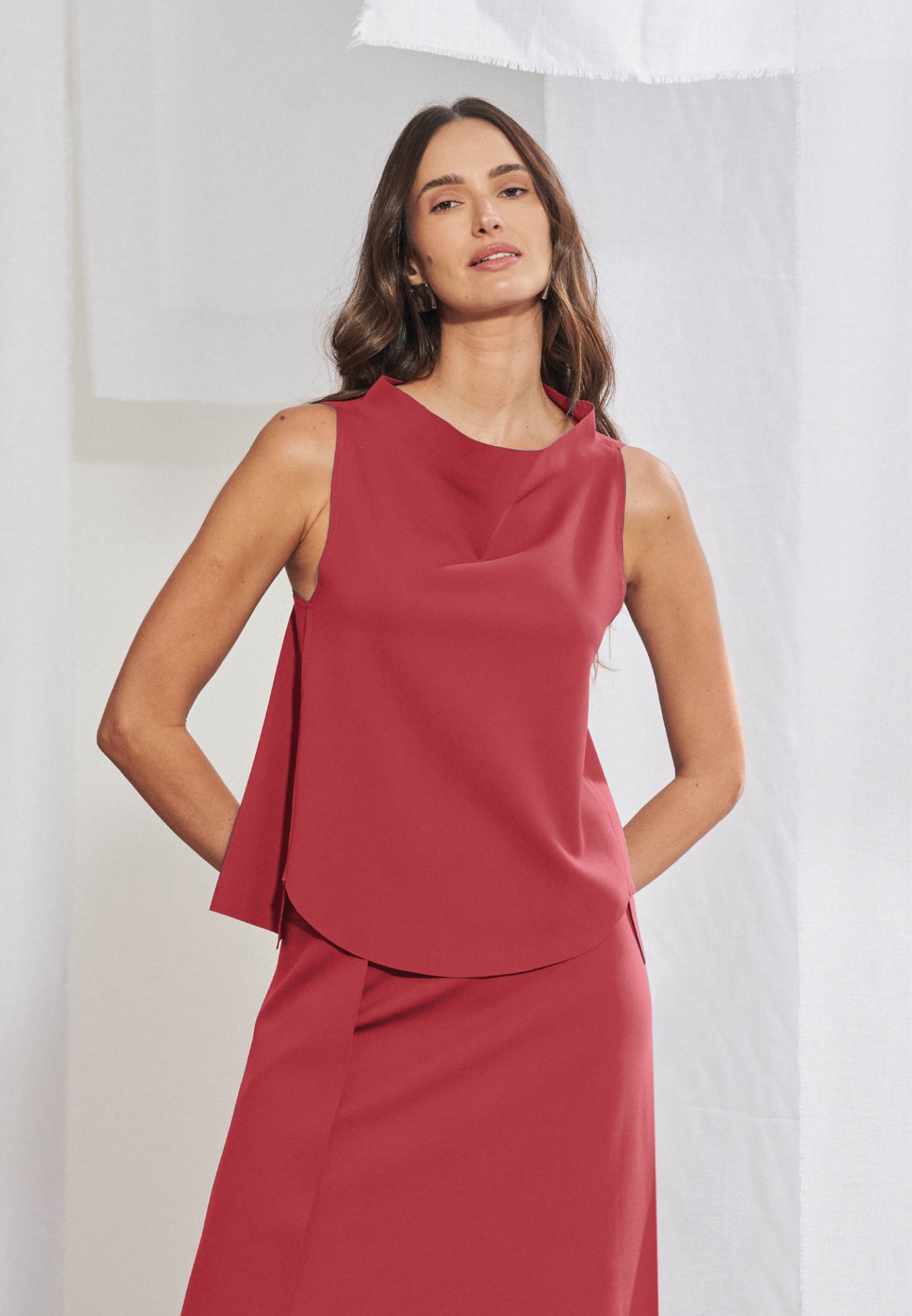 Blusa feminina sem mangas em malha tech. Gola alta transpassada com construção assimétrica degagê, modelagem evasê com barra frontal abaulada e acabamento a fio nas bordas. Aberturas sobrepostas visíveis nas laterais da frente.