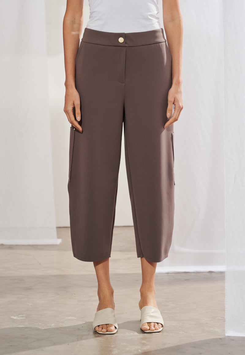 Calça feminina de modelagem ampla, com corte reto. Possui bolsos faca embutidos e apresenta bolsos cargo chapados com rebites metálicos nas laterais. As costas exibem cós com elástico franzido, pala arqueada e dois bolsos traseiros aplicados.