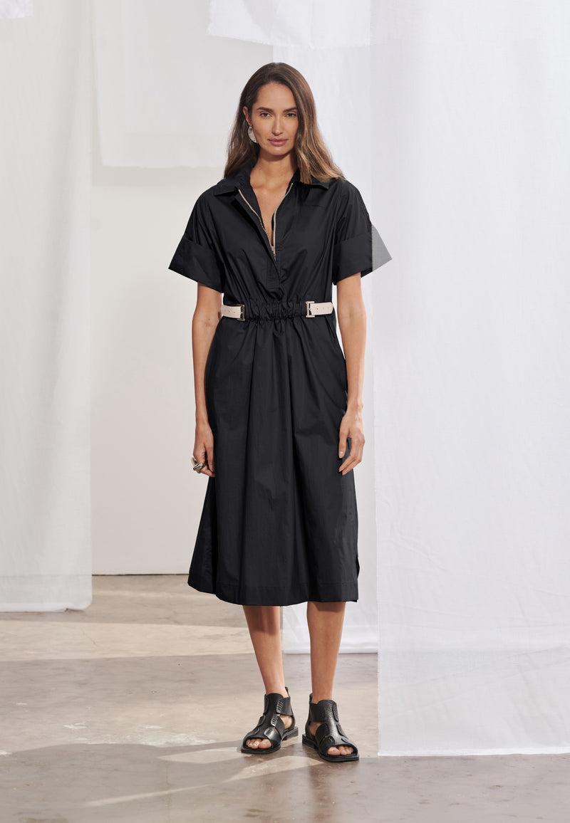 Vestido midi feminino de modelagem reta solta com mangas curtas de punho largo. Possui gola esporte, decote V com zíper tratorado aparente e ajuste na cintura regulável por cinto contrastante e fivela metálica. Saia de comprimento midi com fendas laterais e bolsos faca embutidos.