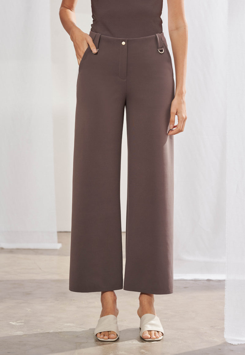 Calça feminina wide leg reta com cós de passantes e duas meias-argolas metálicas aplicadas e bolsos faca laterais. As costas destacam dois bolsos chapados funcionais e recortes geométricos diagonais que se estendem até a barra. Peça com acabamento pespontado simples e caimento estruturado.