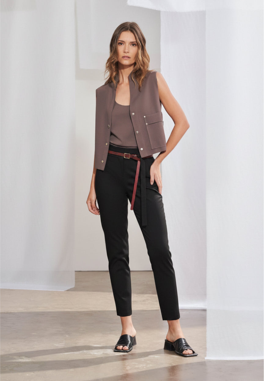 Calça feminina de alfaiataria contemporânea em modelagem cigarrete slim. Na frente, apresenta cós com passantes, bolsos laterais tipo faca e cinto fino de mesmo material. Nas costas, destacam-se dois bolsos traseiros chapados com pontas, recortes anatômicos verticais que descem pelas pernas e terminam em pequenas fendas na barra.