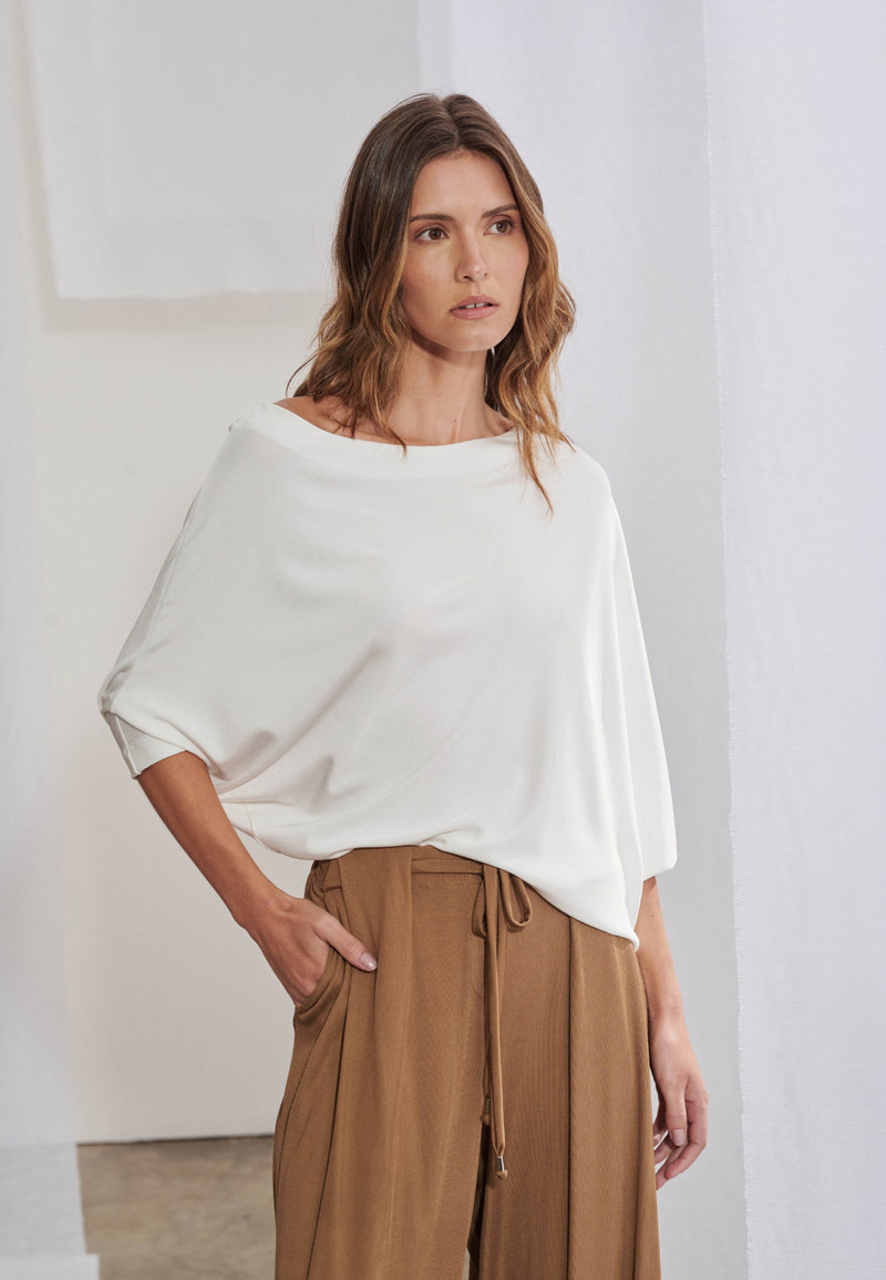 Blusa ampla com efeito blusê e decote canoa assimétrico. Possui mangas 3/4, inteiriças, que cria pregas naturais e trazem volume à lateral e às costas.