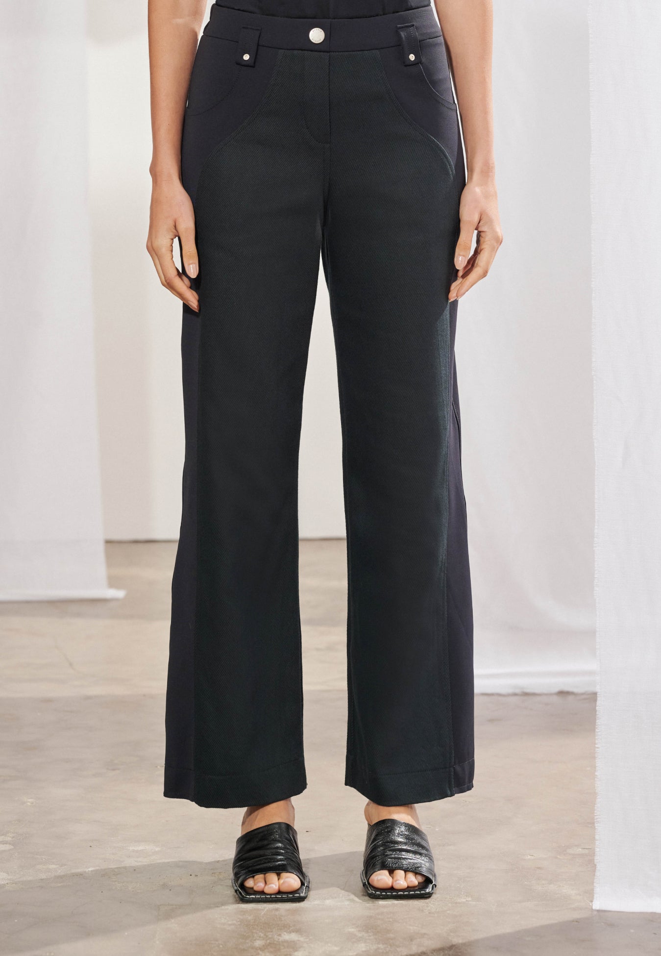 Calça feminina de modelagem reta, com painéis laterais em malha Tech e recortes em sarja 100% algodão. Detalhe de cós anatômico com passantes e botão dourado, exibindo caimento estruturado e confortável no corpo.