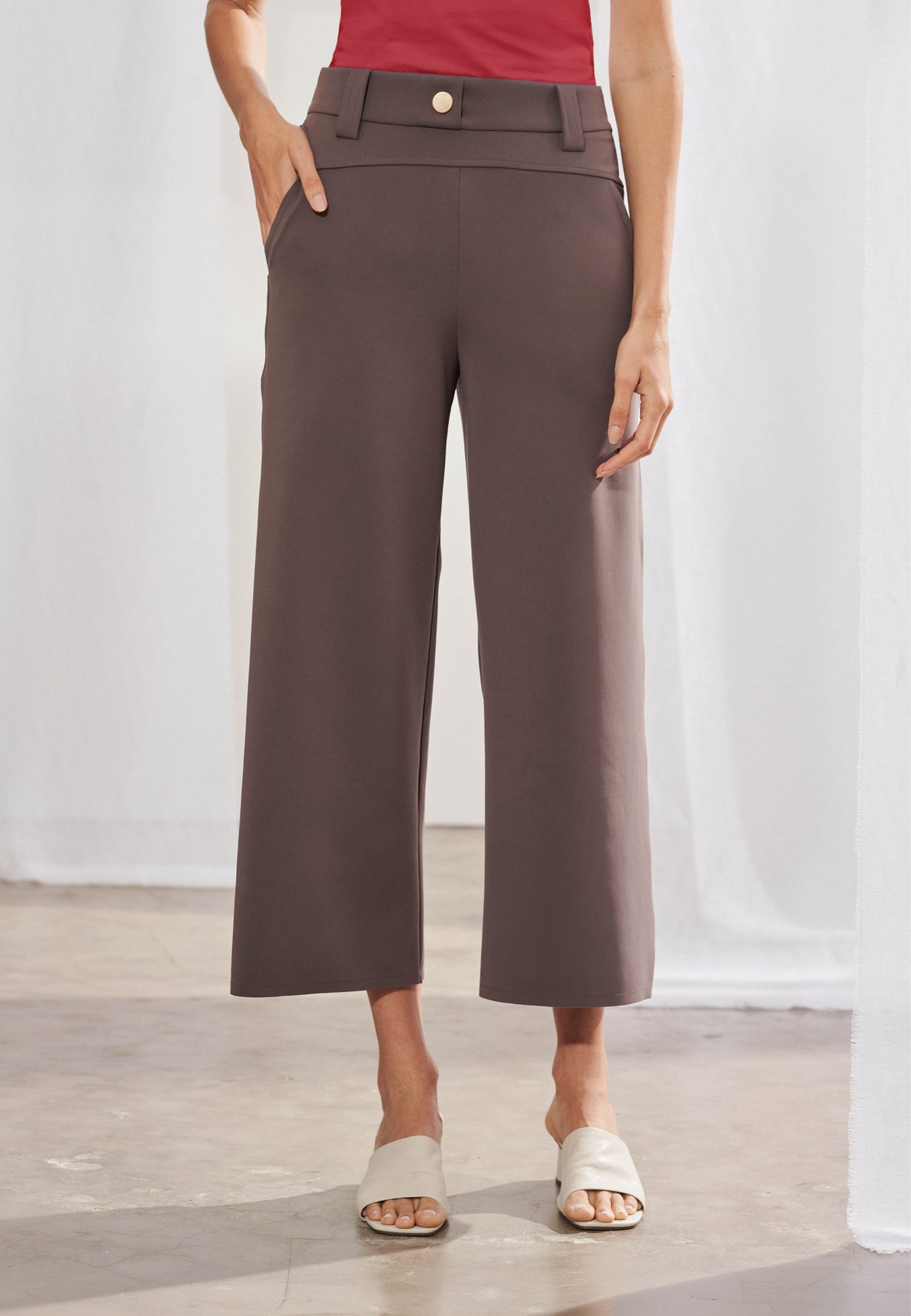 Calça reta feminina em malha tech, vista frontal. Detalhe de pala horizontal costurada abaixo do cós, passante com presilha lateral e barra pespontada. Comprimento até o tornozelo.