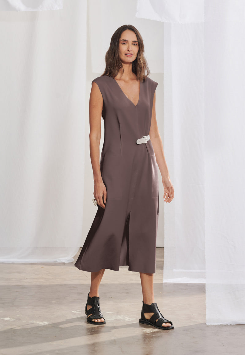 Vestido midi com modelagem levemente acinturada por nervuras verticais na frente e nas costas, mangas tipo japonesas e decote em V. Possui bolsos laterais embutidos e fendas centrais. Acompanha cinto unilateral em couro com fivela metálica. 