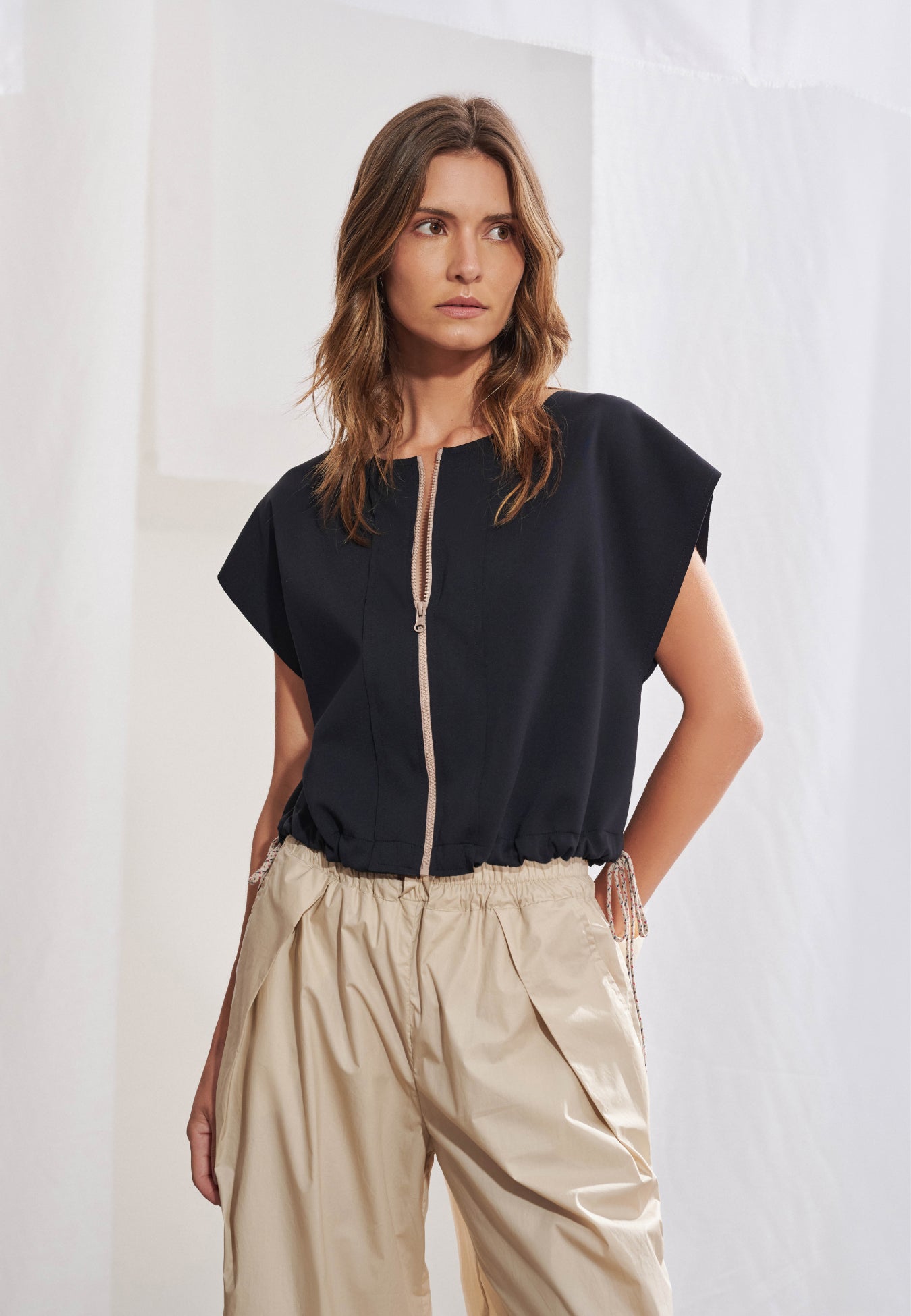 Blusa com zíper frontal destacável, mangas japonesas integradas ao corpo e cordões laterais de regulação da barra. Modelagem solta com efeito blusado em malha Tech. Acabamento a fio.