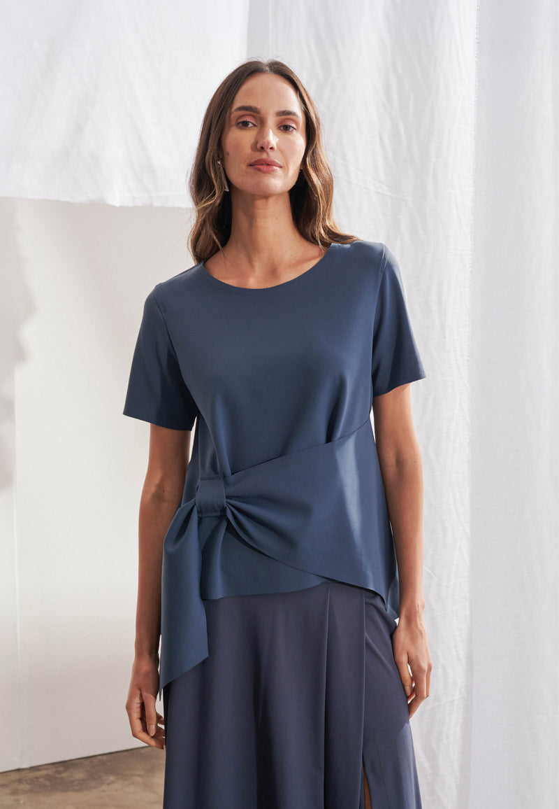 Blusa feminina em malha Tech com decote redondo, transpasse frontal assimétrico com passante largo e manga curta. Modelagem solta com caimento limpo na linha do quadril.