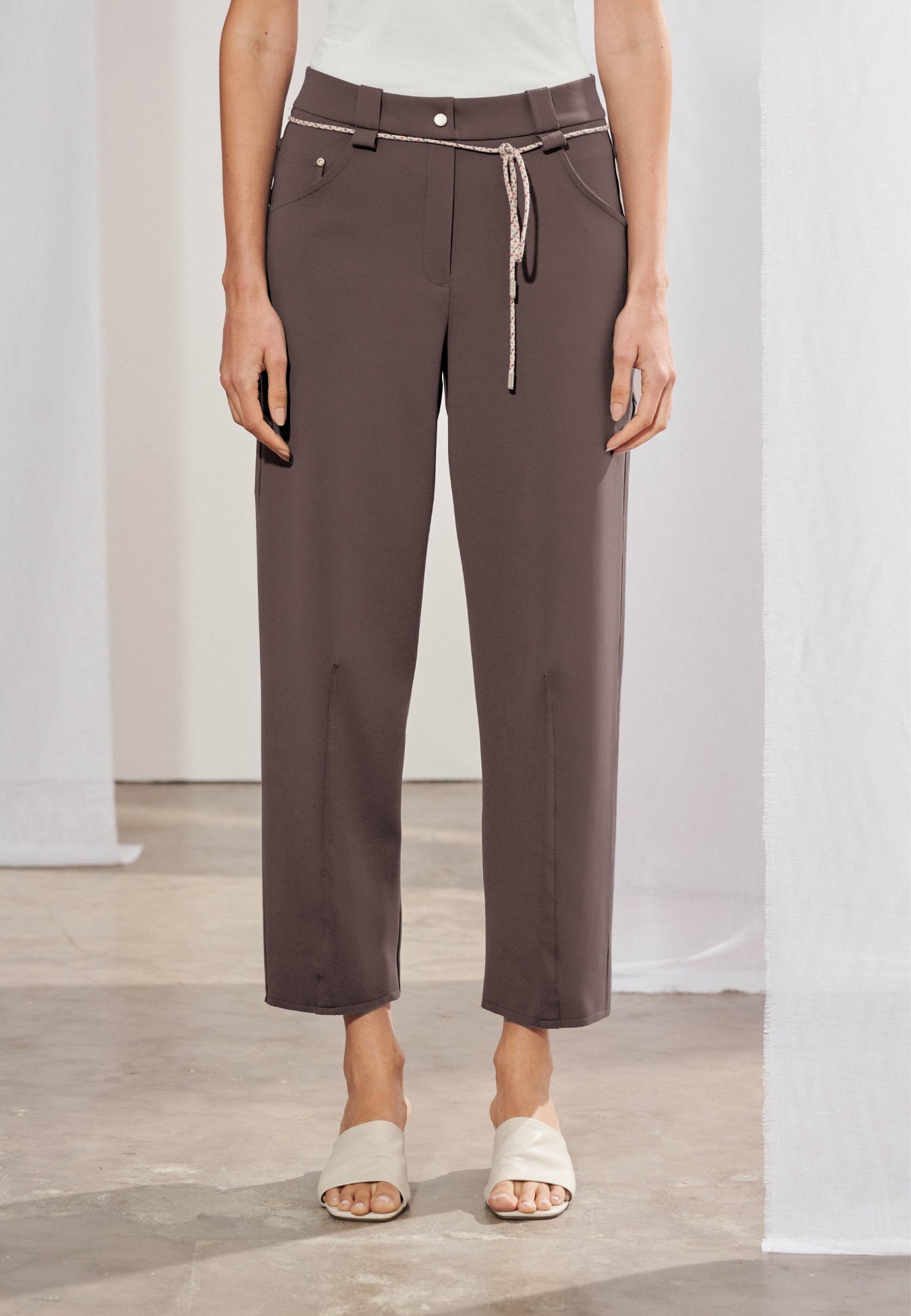 Calça de alfaiataria feminina com modelagem reta e leve afunilamento na barra. Cós com passantes e elástico posterior. Nervuras verticais centralizadas na frente das pernas. Cinto em cordão fino com ponteiras metálicas. Vista frontal e posterior.