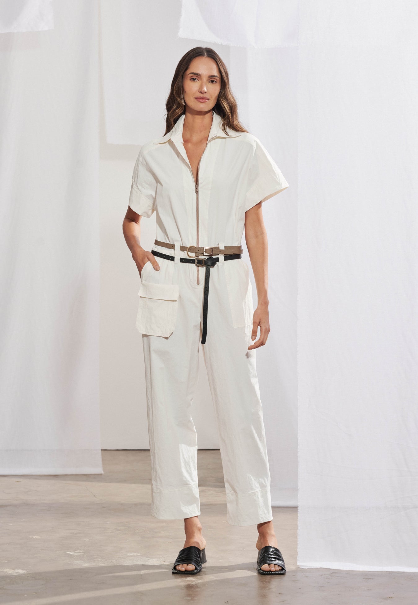 Macacão longo utilitário feminino em malha air com estampa exclusiva visível nas costas. Gola colarinho esporte, fechamento frontal por zíper, bolso cargo com lapela retangular na lateral e cós com elástico. Vista traseira destacando a estampa localizada.