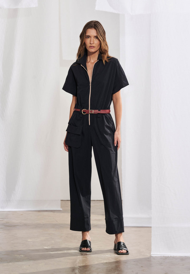 Macacão longo utilitário feminino em malha air com estampa exclusiva visível nas costas. Gola colarinho esporte, fechamento frontal por zíper, bolso cargo com lapela retangular na lateral e cós com elástico. Vista traseira destacando a estampa localizada.