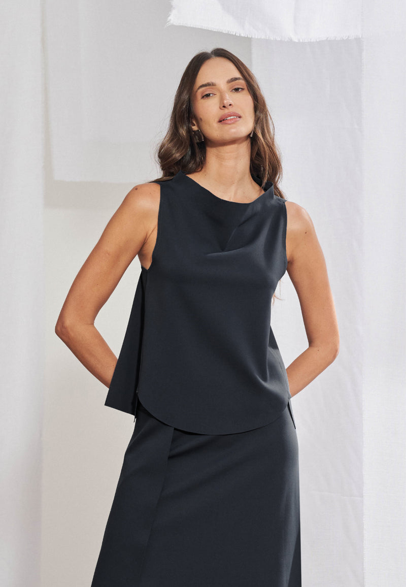 Blusa feminina sem mangas em malha tech. Gola alta transpassada com construção assimétrica degagê, modelagem evasê com barra frontal abaulada e acabamento a fio nas bordas. Aberturas sobrepostas visíveis nas laterais da frente.